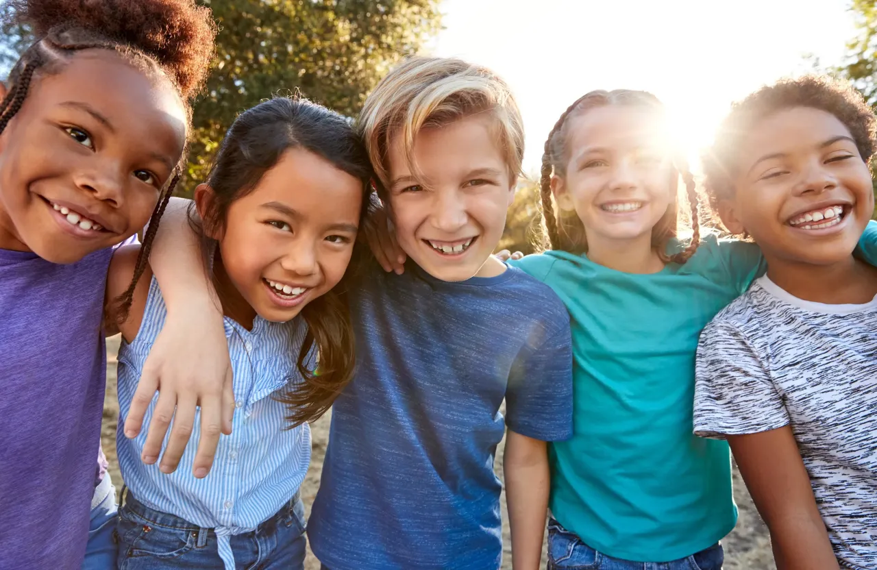 Group of kids looking at camera, sun behind them.