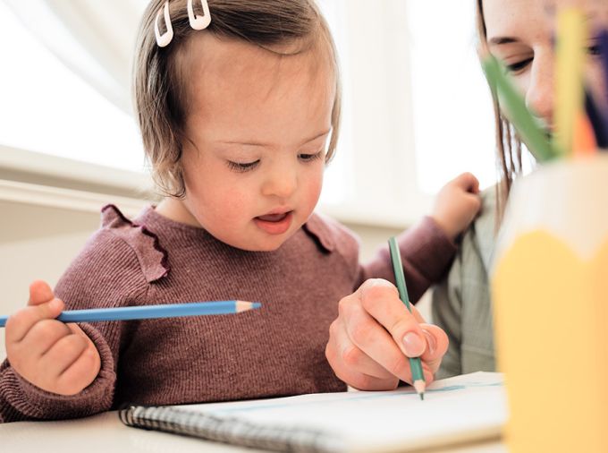 Child with Down Syndrome using colored pencils.