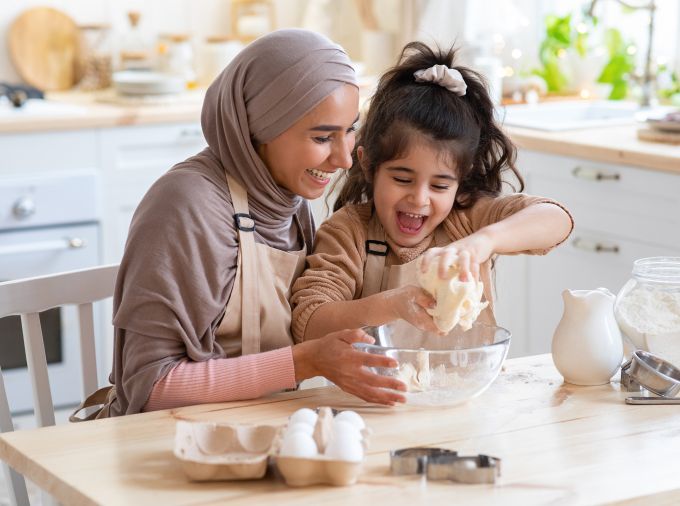 Mother and daughter making dough in their kitchen.