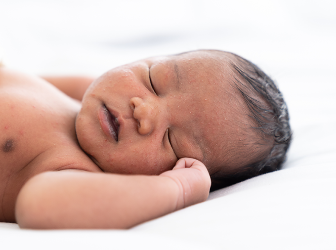 Sleeping newborn baby with dark skin.