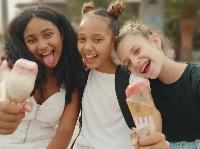 Three tween girls eating ice cream and making faces at the camera.