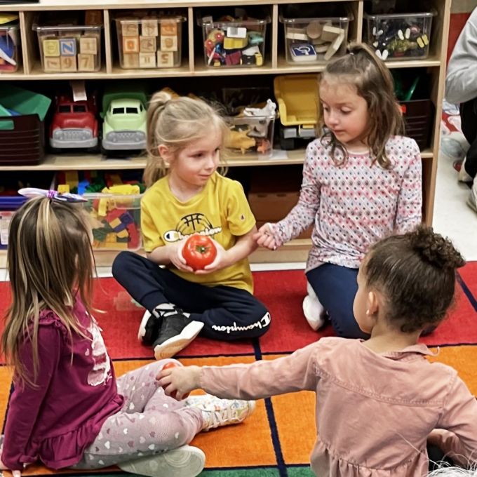 Preschool students passing around tomatoes