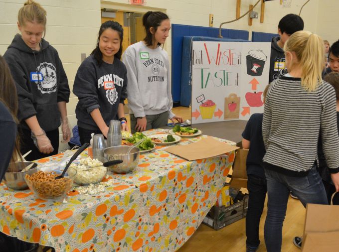 Penn State students at a table with food to distribute in all purpose room.